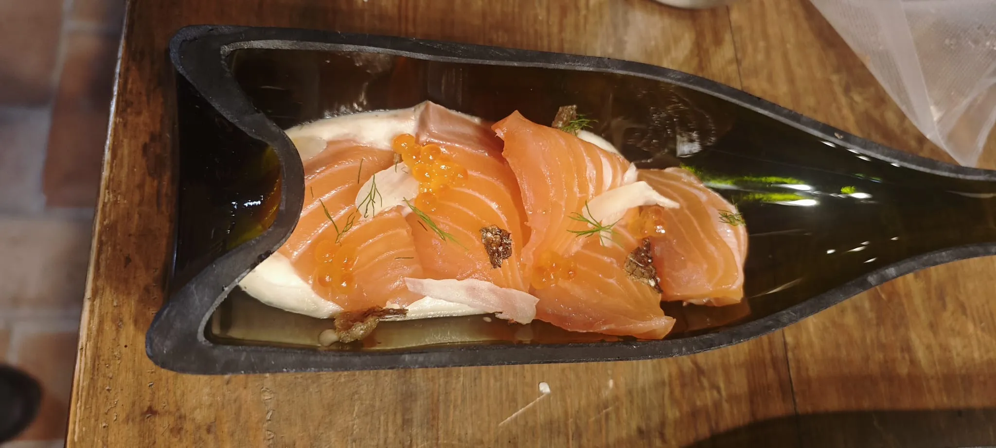 Salmó amb crema, ous de salmó i anet, servit dins una ampolla de vidre tallada i aplanada