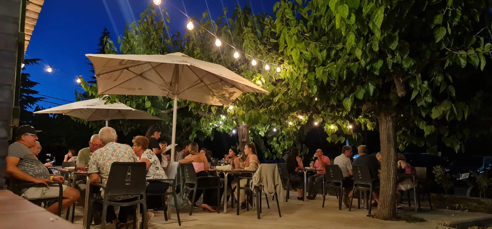 La terrassa del Mas Pla al vespre, amb bombetes penjades i les taules plenes
