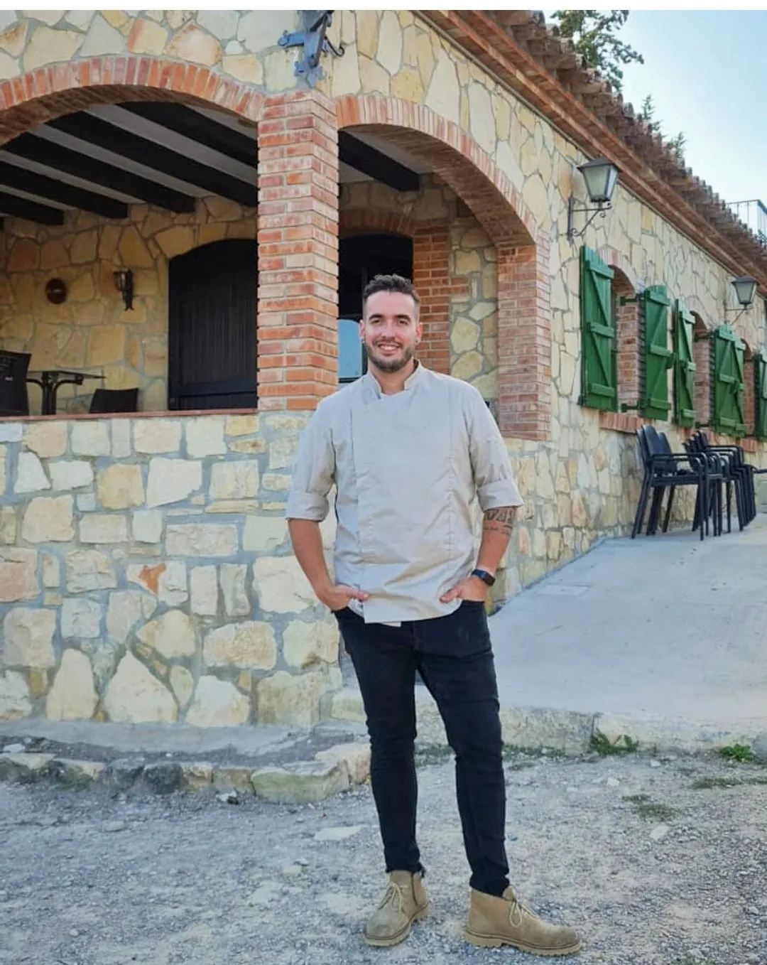 L’Adrián Fernández, amb la jaqueta de cuina, davant el porxo d’arcs del Mas Pla